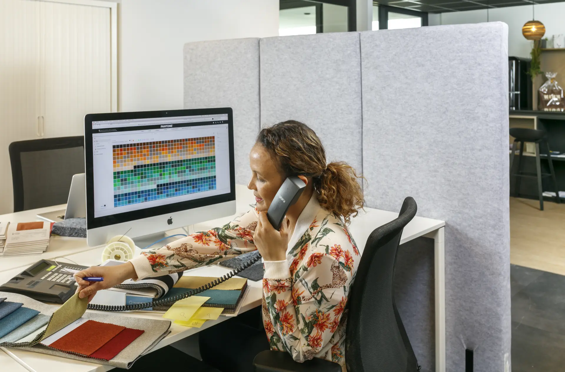 Femme au téléphone à son poste de travail équipé de cloisons acoustiques