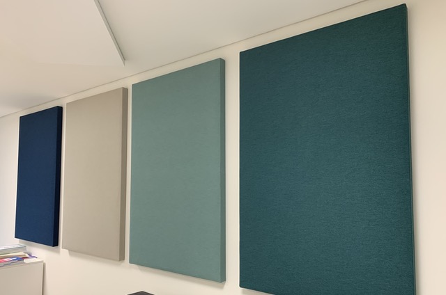Akoestische wandpanelen in blauw en groenblauw aan een wand