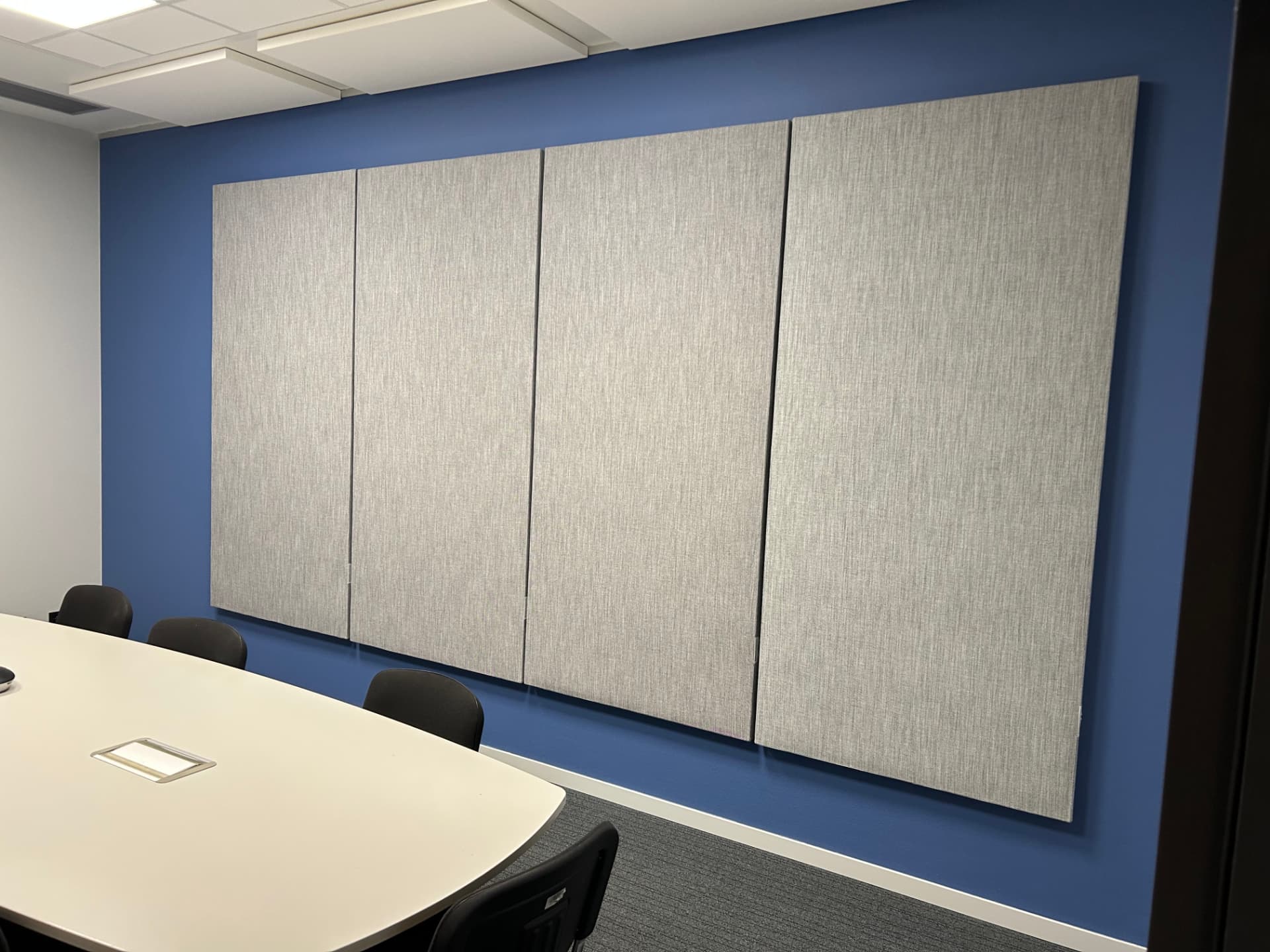 Grijze akoestische wandpanelen aan een blauwe wand in een vergaderruimte