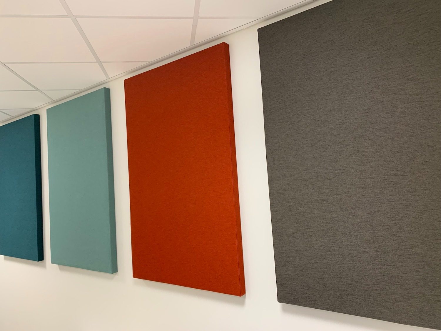 Kleurrijke akoestische wandpanelen in groenblauw, oranje en grijs