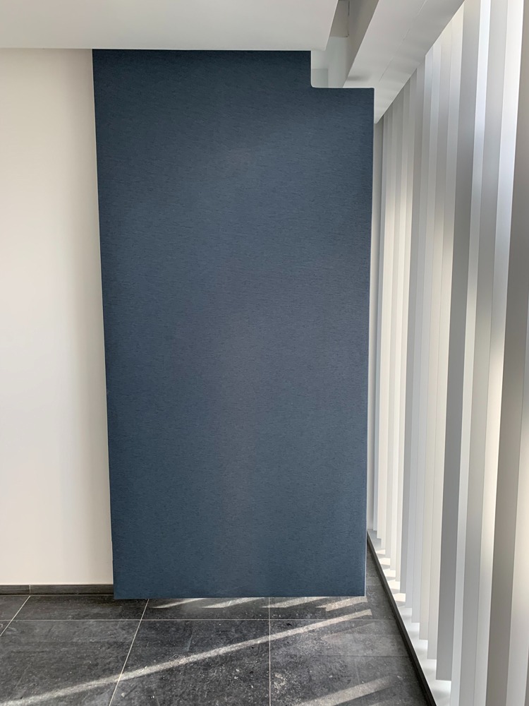 Vrijstaande akoestische scheidingswand in blauwgrijs langs een raampartij