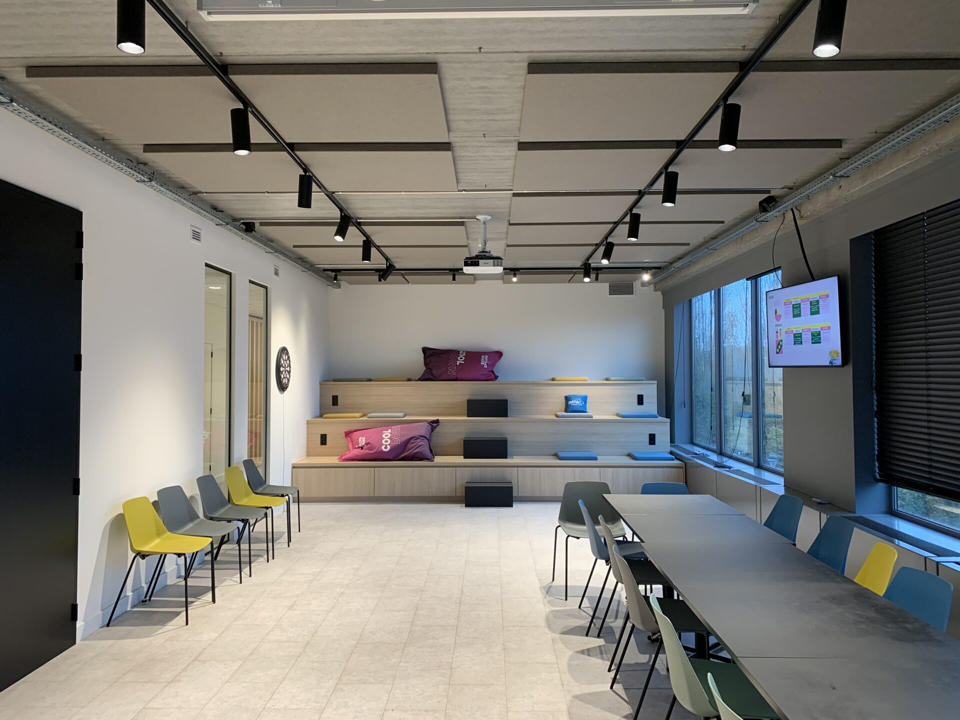Strak afgewerkte akoestische plafondpanelen in een vergaderruimte, gemonteerd op een betonnen plafond voor geluidsdemping en betere akoestiek.