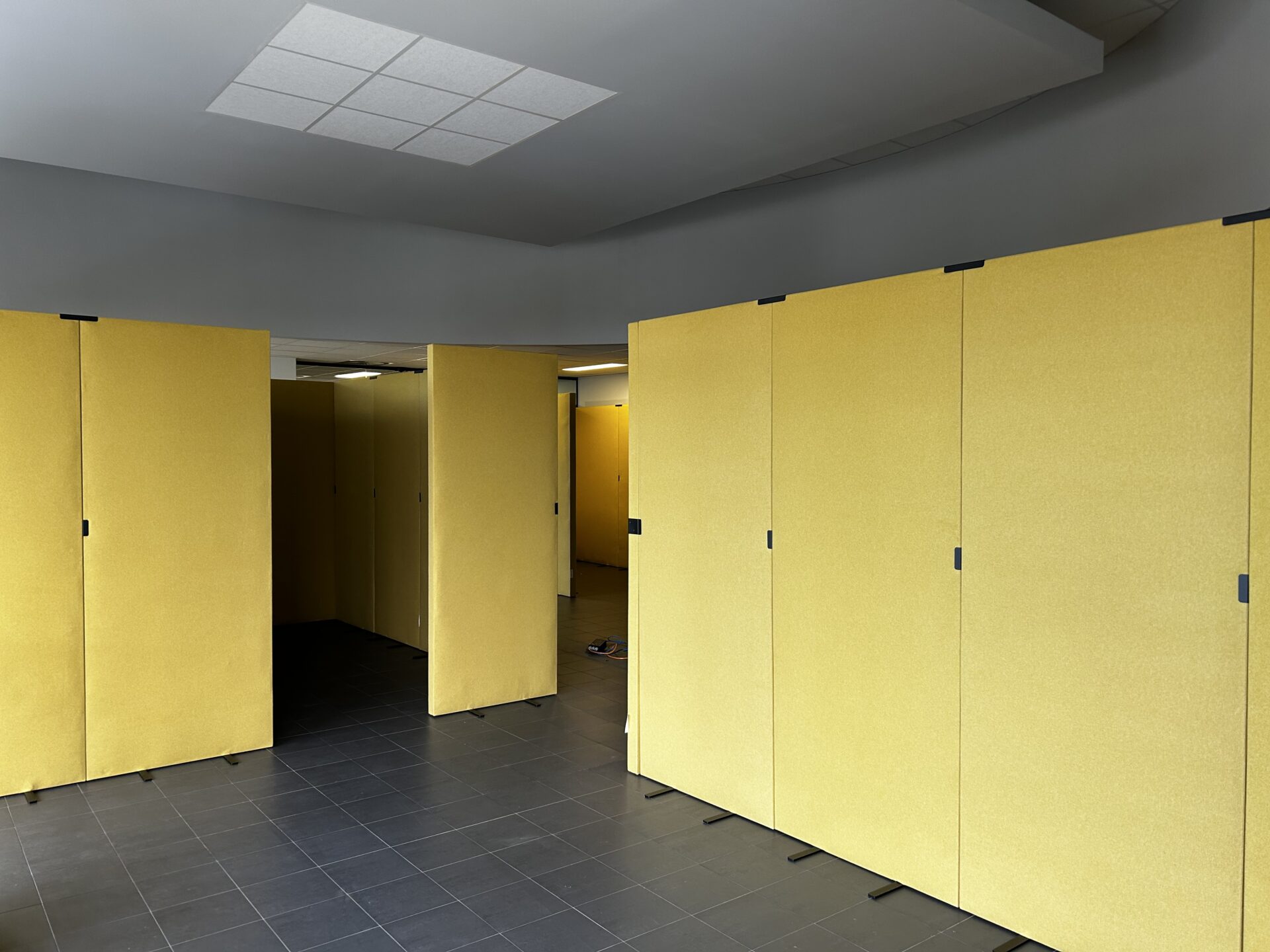 Hoge gele akoestische panelen als vrijstaande ruimteverdelers, gecombineerd met een ingebouwd akoestisch plafondpaneel voor geluidsdemping
